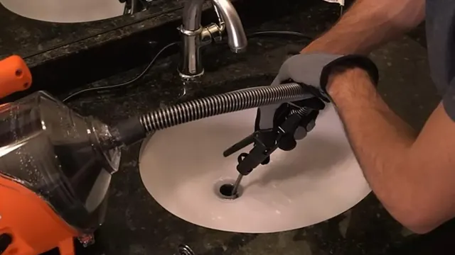 Plumber's hands feeding a drain snake into a bathroom sink drain