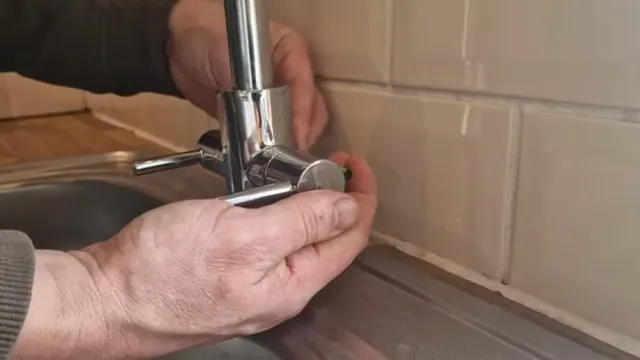 Hands loosening the fitting on a kitchen faucet