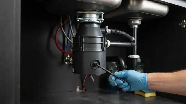 Hand using a hex key on a garbage disposal under a kitchen sink